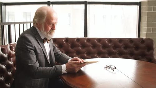 Senior Man Looking at Tablet at Table