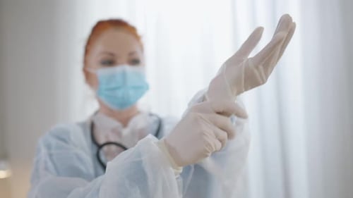 Healthcare Worker puts on Gloves Before Examination