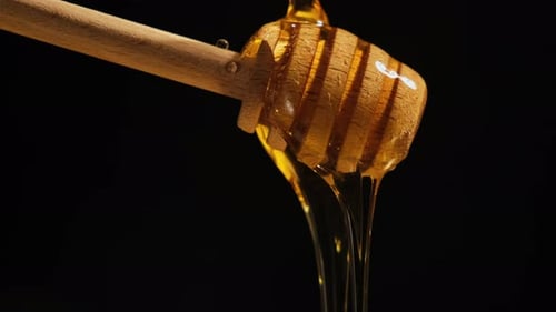 Honey Flowing From Honey Spoon on Black Background