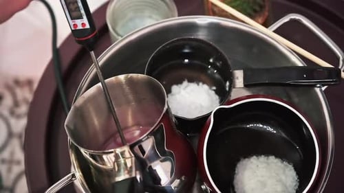 Hand made candles production, female hand mixing melting wax in pots. Slow motion