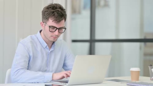 Young Man Working on Laptop at Desk