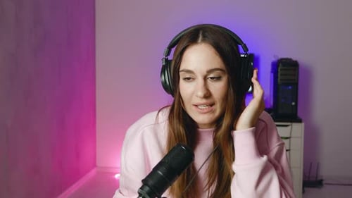 Young Female Singer Woman in Headphones Singing in Microphone Recording Podcast in Studio with