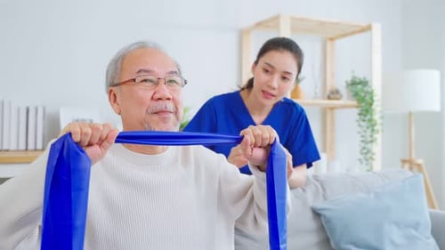 Senior Man Exercising with Resistance Band with Caregiver