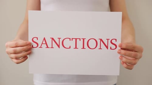 Close Up of a Protester Hands Holding Cardboard Banner with the Words Sanctions