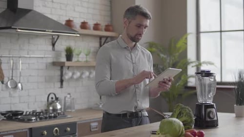 Man Uses Tablet While Cooking in Kitchen