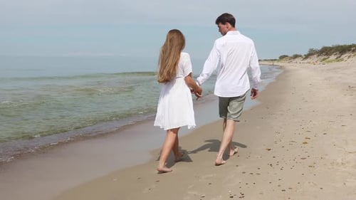Cute Couple of Young Lovers Walk Along The Beach