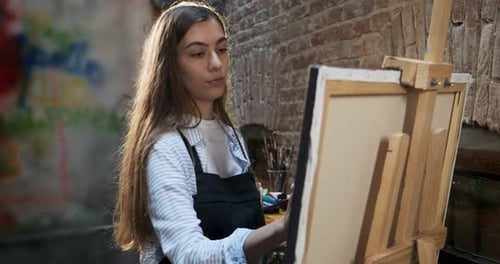 Woman Artist Painting at Easel Indoors
