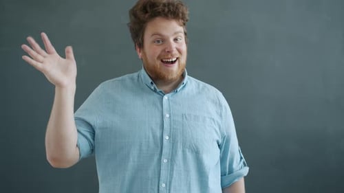 Cheerful Man Waving Hello on Gray Background
