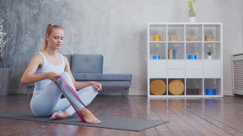 Woman Stretching Legs Using Resistance Band at Home