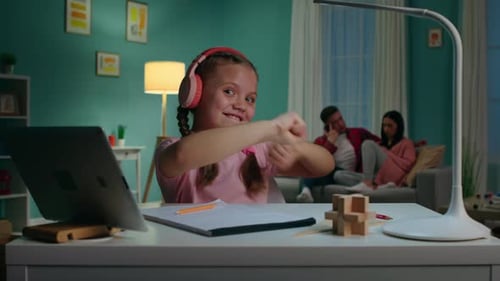 Smiling Girl Dances While Using Laptop at Desk