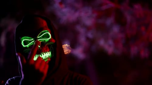 Hooded Figure with a Glowing Skull Mask at Night