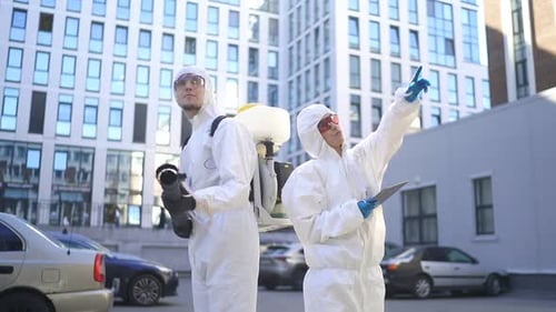 Workers in Protective Suits Next to Modern Building