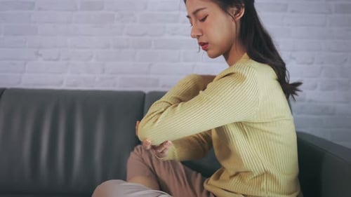 Woman Massaging Sore Arm on Couch