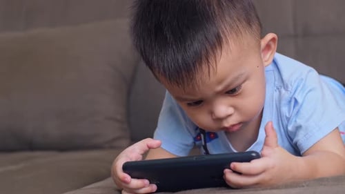 Infant Enjoys Smartphone on Couch Indoors