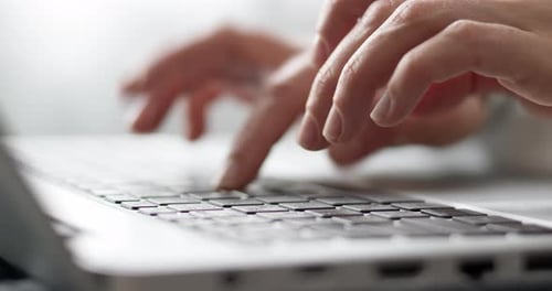 Female hands are typing on a laptop keyboard, close-up.