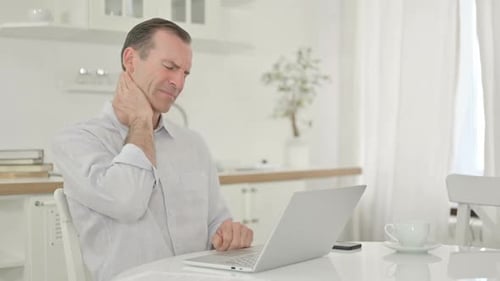 Man Working at Laptop Rubs Stiff Neck