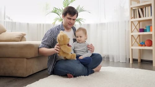 Baby boy with father having fun and playing with teddy bear