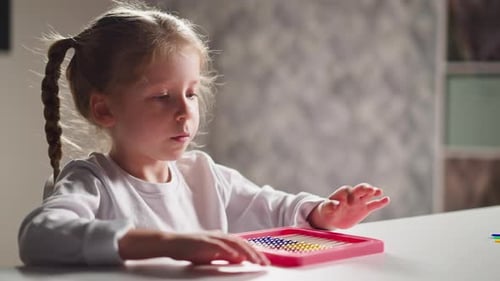 Niña estudiante juega con un ábaco colorido sentado en la mesa