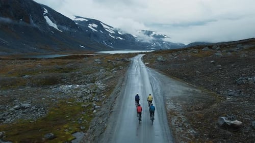 Cyclists Ride Through a Wet Mountain Valley