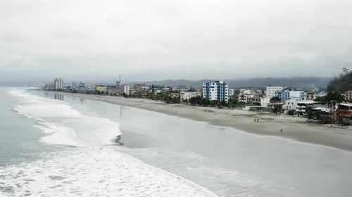 Vista aérea sobre uma praia repleta de edifícios em um dia nublado no Equador