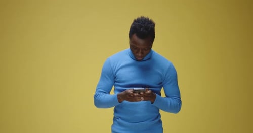 Adult Typing on Cellphone Against Yellow Background