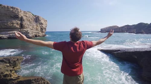 Young Man Enjoying Coastal View With Arms Outstretched