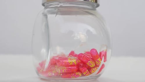 Glass jar with pink and yellow capsules
