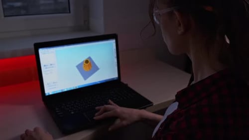 Kreative Designerin drückt den Knopf auf dem Bedienfeld des 3D-Druckers, um ihn beim Sitzen zu starten