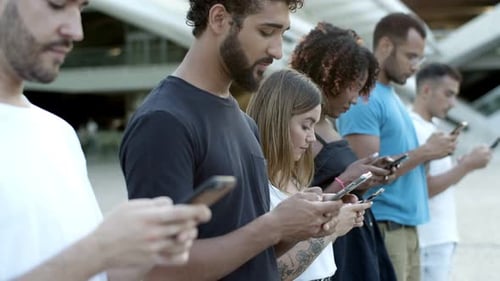 Pensive Young Friends Using Smartphones on Street