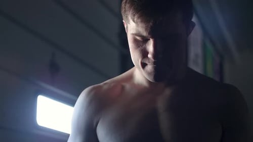 Low angle shot of a young attractive muscular MMA fighter in a moody light bouncing on his feet with