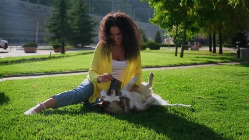 Woman Playing with Dog on Grass in Park
