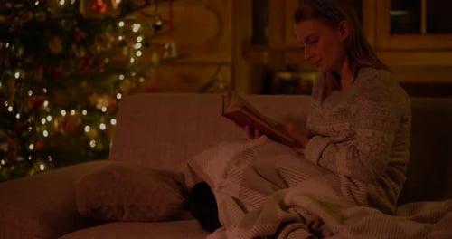 Woman Reading by Christmas Tree in Cozy Home