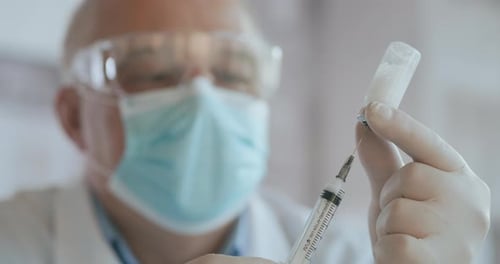 Doctor Hand hält eine Spritze und eine blaue Impfstoffflasche im Krankenhaus. Gesundheits- und medizinische Konzepte