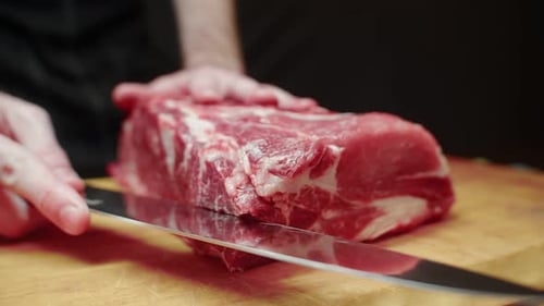 Slicing Raw Meat on a Wooden Cutting Board