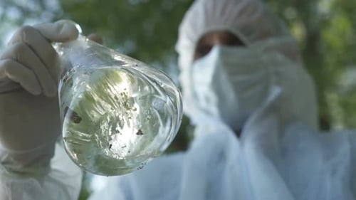 Scientist in Suit Holds Flask With Organic Matter
