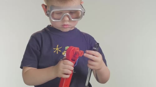 Young Child with Safety Goggles Playing with Toy Tools