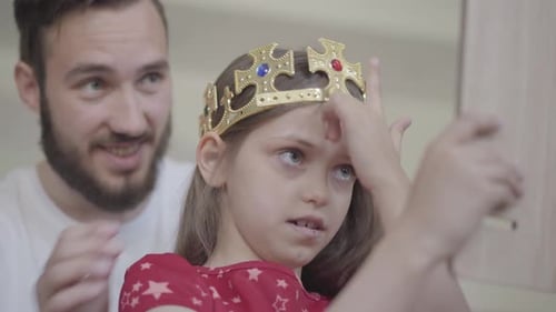 Little Girl Smiles Wearing Crown with Father