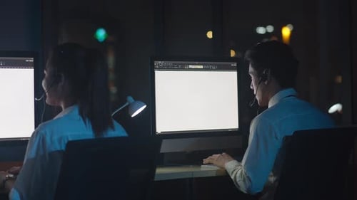 Call center team using computer and microphone headset working technical support in night office