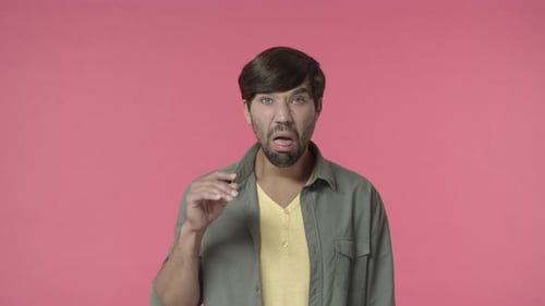 Man Licking Finger, Gesturing in Front of Pink Backdrop