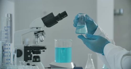 Researcher Examining Blue Liquid in a Laboratory