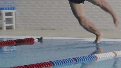 Joven deportista nadador se sumerge en el agua de una piscina de entrenamiento