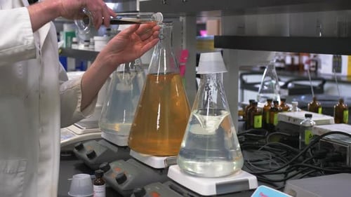 Scientist Adds Dark Liquid to Beaker in Laboratory