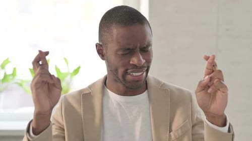 Man Wishing with Fingers Crossed Indoors