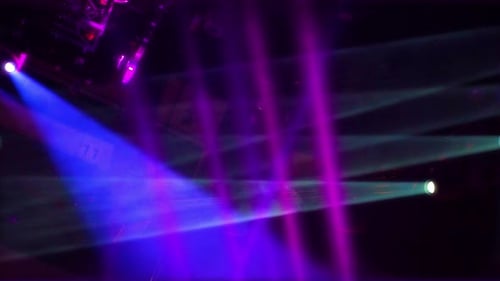 Multiple colorful turned on stage lights mounted to ceiling flashing in the dark room. Concert hall