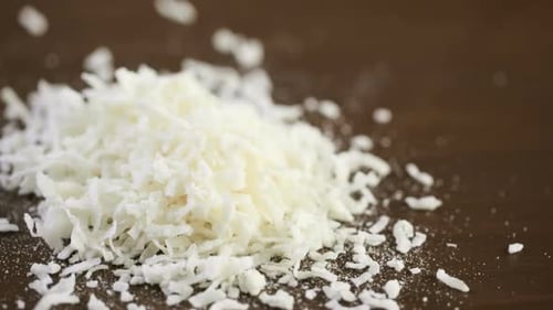 Dehydrierte Kokosflocken auf Holzuntergrund.