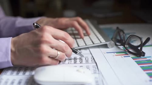 Hands Typing and Writing at Desk with Data