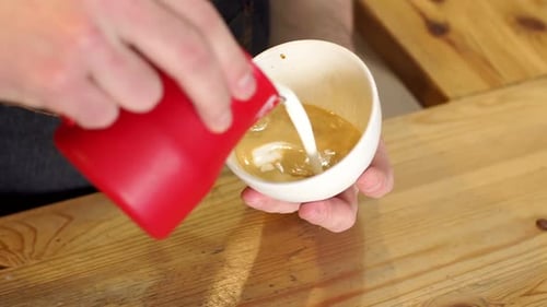 Primer plano de manos vertiendo la leche caliente en la taza de café