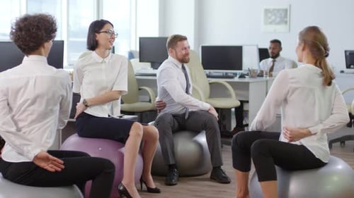 Employees Exercising on Fitness Balls in Office