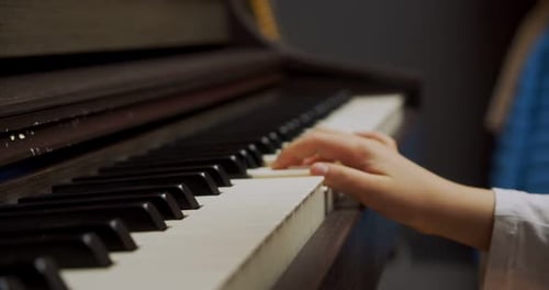 Child Plays Piano Keys Close Up