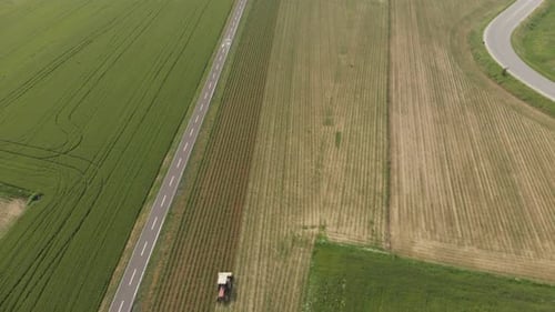 Aerial: tractor working on cultivated fields farmland, agriculture occupation, top down view
